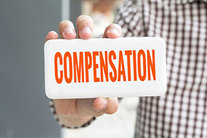 man holding a sign that reads compensation